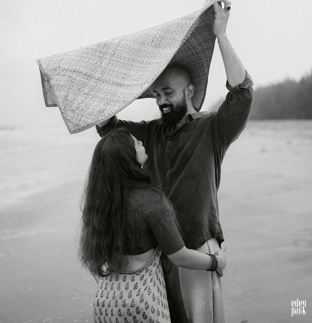 A couple embracing beneath a veil by the water